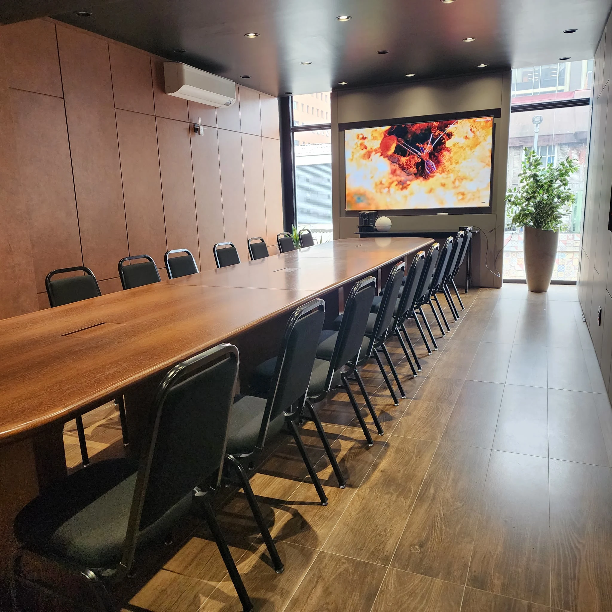 Mesa longa montada para evento empresarial no Espaço Convivium, com cadeiras dos dois lados e vista da cozinha-show ao fundo